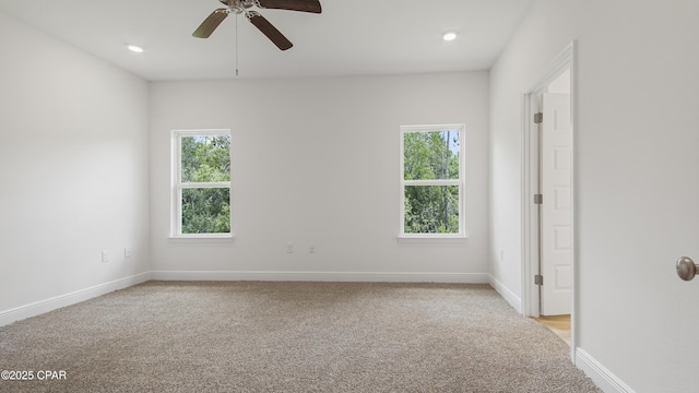 unfurnished room featuring light colored carpet, baseboards, a ceiling fan, and plenty of natural light