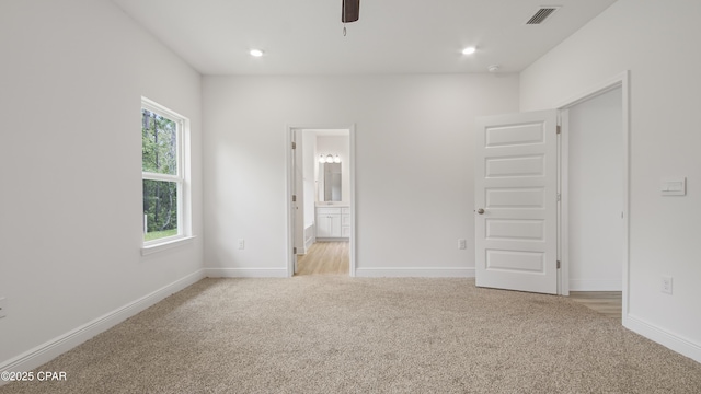 unfurnished bedroom with connected bathroom, light carpet, visible vents, and baseboards