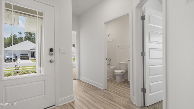 foyer with light wood-style flooring and baseboards