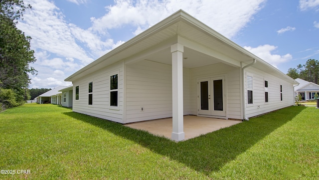 back of property with a patio area, french doors, and a yard