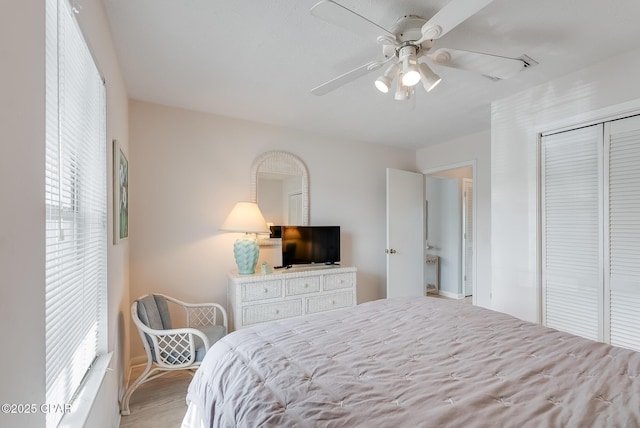 bedroom with a ceiling fan, wood finished floors, and a closet