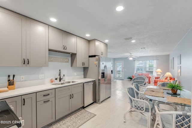 kitchen featuring a sink, ceiling fan, stainless steel appliances, gray cabinetry, and visible vents