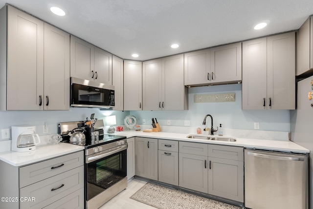 kitchen featuring appliances with stainless steel finishes, gray cabinets, and a sink