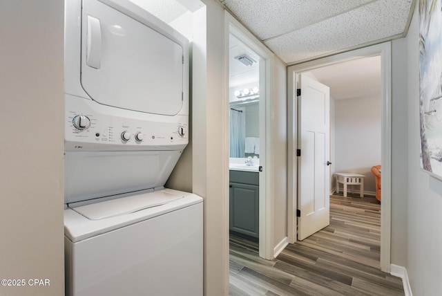 17155 Front Beach Rd Unit E602, Panama City Beach, FL 32413 - laundry area featuring stacked washing machine and dryer, wood finished floors, and baseboards