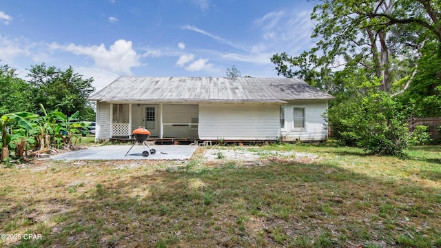 rear view of property featuring a lawn, fence, a patio, and metal roof