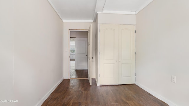 unfurnished bedroom featuring baseboards, dark wood-style floors, a closet, and ornamental molding