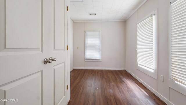 empty room with visible vents, baseboards, wood finished floors, and a wealth of natural light