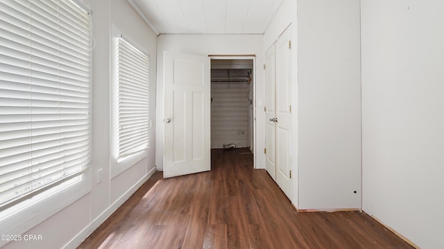 unfurnished bedroom featuring a spacious closet, wood finished floors, a closet, and multiple windows