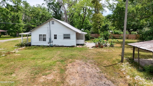 view of side of home featuring a lawn and fence