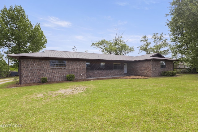 back of house with a yard, brick siding, and metal roof