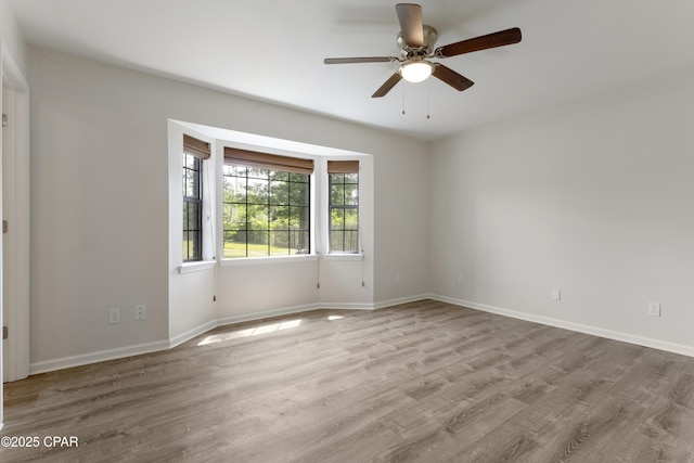 unfurnished room with baseboards, wood finished floors, and ceiling fan
