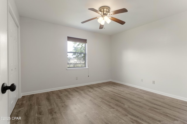 spare room featuring baseboards, wood finished floors, and ceiling fan