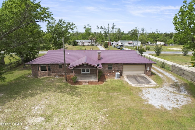 ranch-style house featuring driveway, a front lawn, metal roof, and brick siding