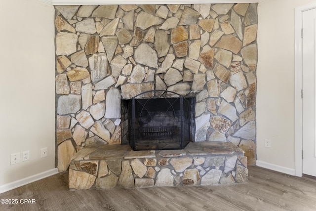 details featuring a stone fireplace, wood finished floors, and baseboards