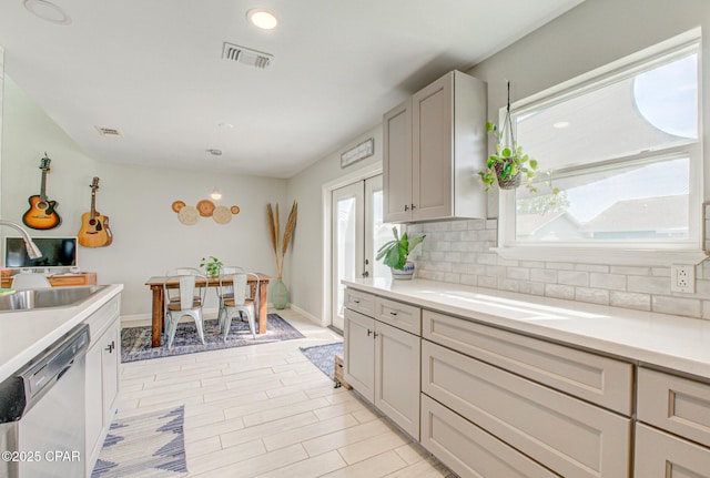 kitchen with a sink, decorative backsplash, stainless steel dishwasher, and visible vents