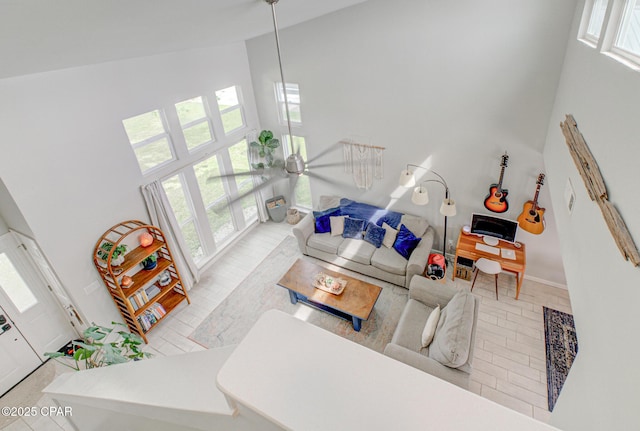 living area with baseboards, a healthy amount of sunlight, and high vaulted ceiling