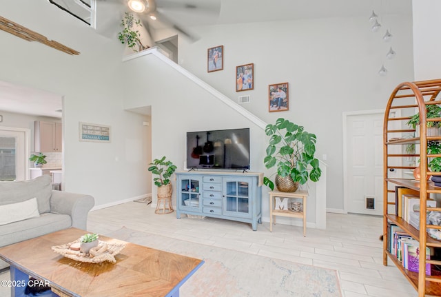 living area featuring high vaulted ceiling, visible vents, wood finish floors, and baseboards