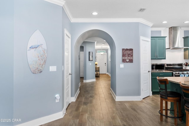 hall featuring ornamental molding, baseboards, dark wood-style floors, recessed lighting, and arched walkways