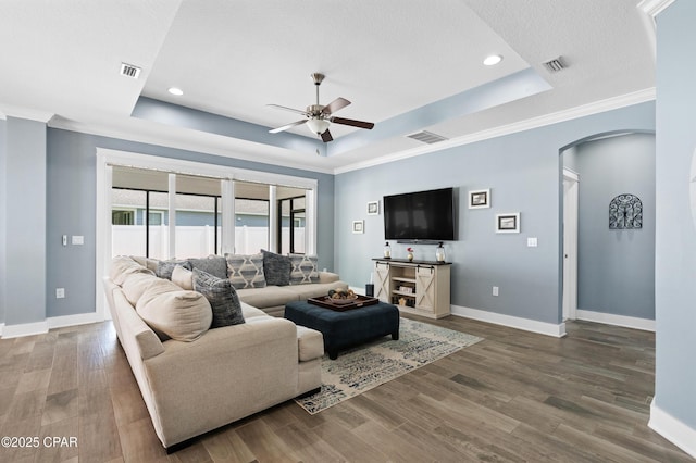 living area featuring arched walkways, a tray ceiling, visible vents, and ceiling fan