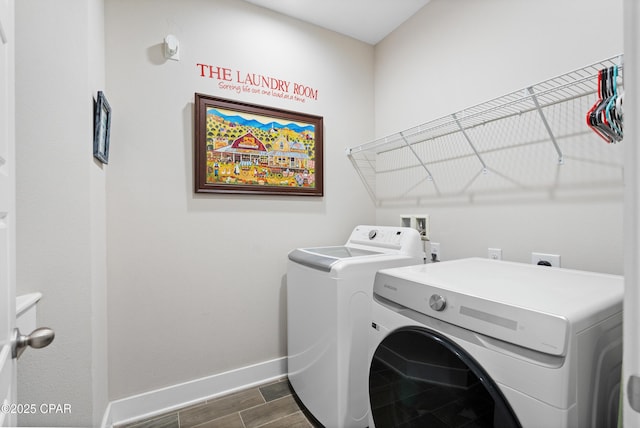 clothes washing area with baseboards, laundry area, dark wood-type flooring, and washing machine and clothes dryer