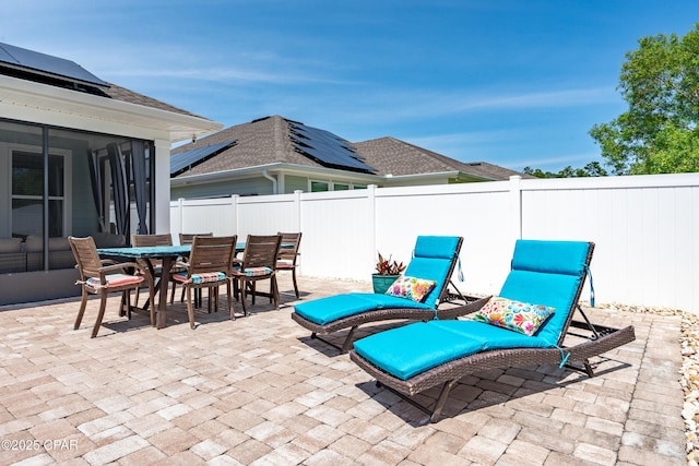 view of patio / terrace featuring outdoor dining area, a fenced backyard, and a sunroom