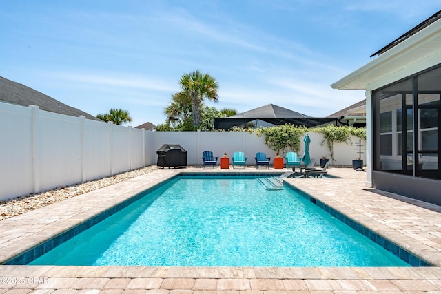 view of swimming pool featuring a patio, a fenced in pool, a fenced backyard, and a sunroom