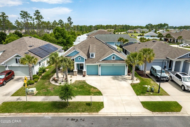 view of front of property with an attached garage, driveway, a residential view, and a front yard
