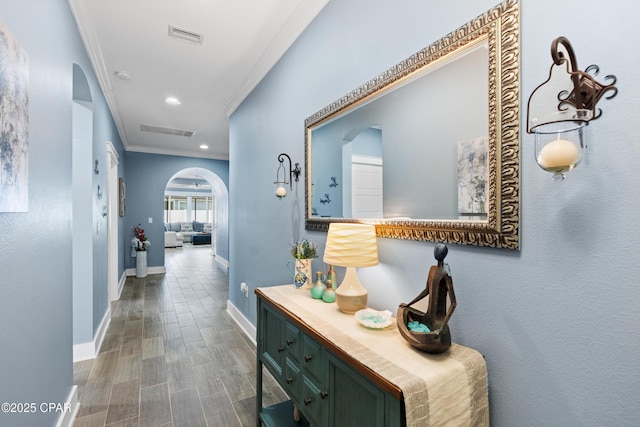 hall featuring crown molding, arched walkways, and baseboards
