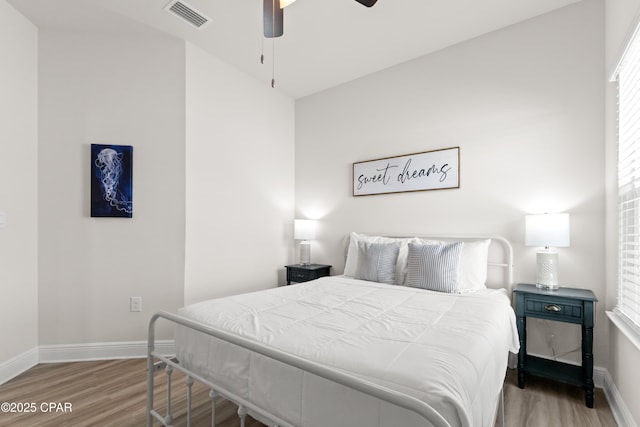 bedroom featuring baseboards, multiple windows, wood finished floors, and visible vents
