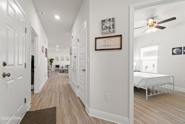 hall featuring light wood-type flooring, recessed lighting, and baseboards