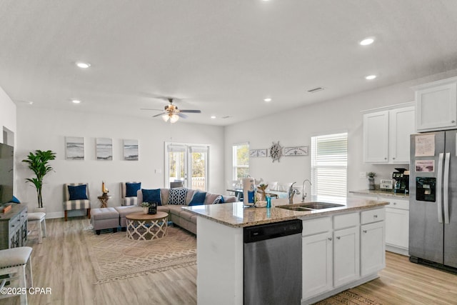 kitchen with white cabinets, stainless steel appliances, a sink, and light wood-style floors