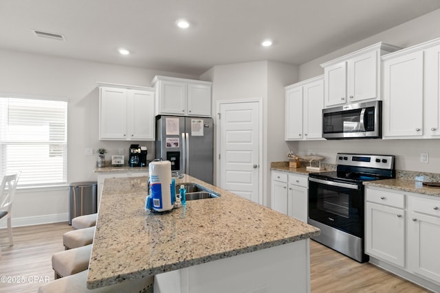 kitchen featuring stainless steel appliances, visible vents, a breakfast bar, and white cabinetry