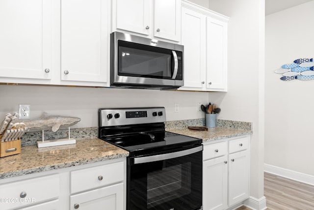 kitchen with white cabinetry, appliances with stainless steel finishes, and light stone counters