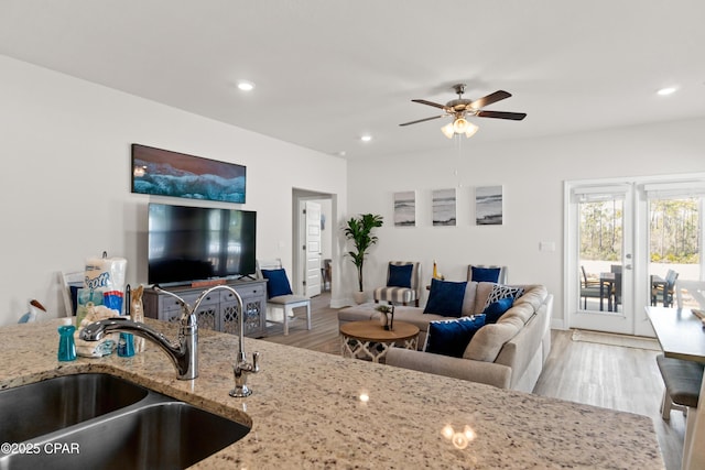 living area featuring light wood-type flooring, a ceiling fan, baseboards, and recessed lighting