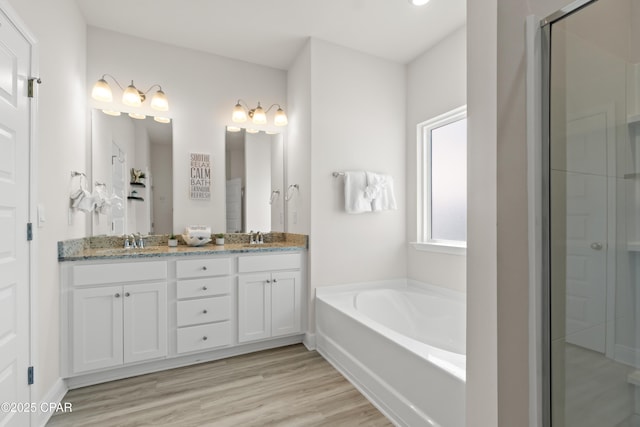 full bath featuring a garden tub, a sink, wood finished floors, and a shower stall