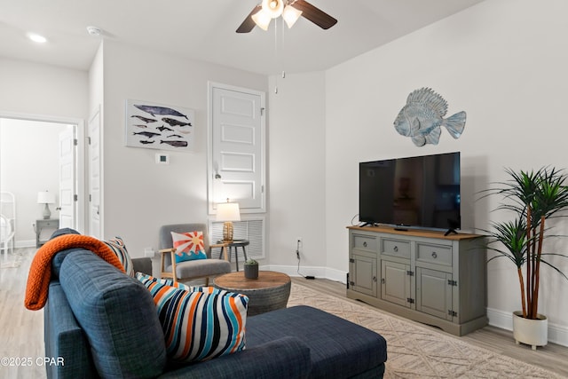 living area featuring baseboards, ceiling fan, and light wood-type flooring