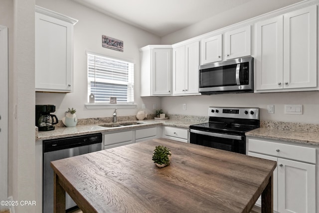 kitchen featuring stainless steel appliances, white cabinetry, and a sink