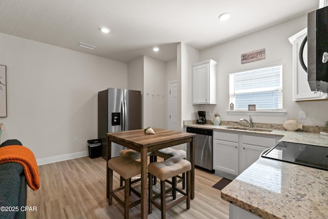 kitchen with light wood-style floors, a sink, recessed lighting, and stainless steel appliances
