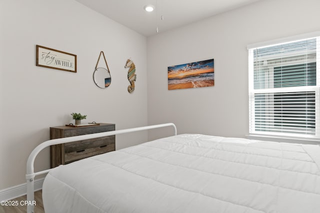 bedroom featuring baseboards, multiple windows, and wood finished floors