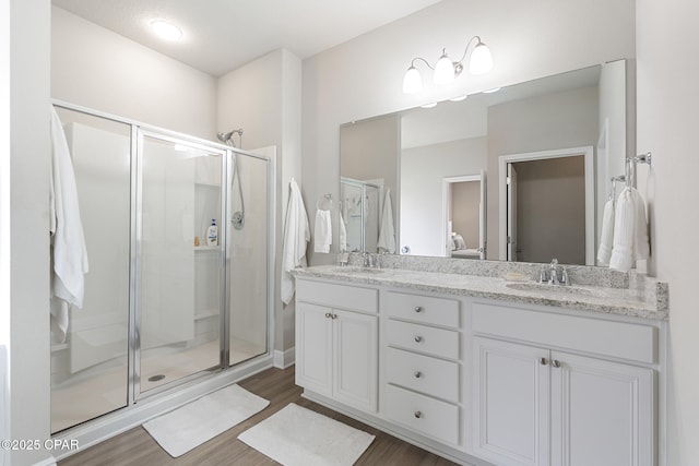 bathroom with double vanity, a shower stall, and a sink