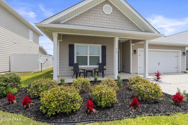 view of front of property featuring concrete driveway, an attached garage, fence, and covered porch