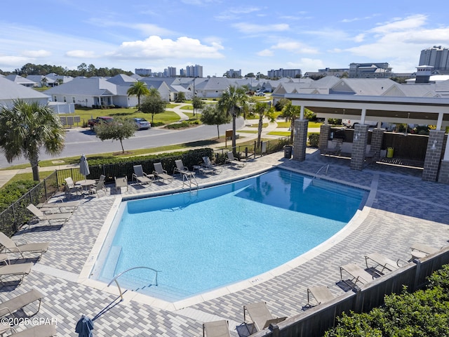 pool with fence, a patio area, and a residential view