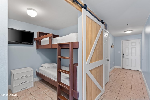 bedroom with a barn door, baseboards, and tile patterned flooring