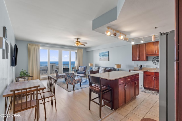 kitchen featuring a sink, freestanding refrigerator, white dishwasher, ceiling fan, and light countertops