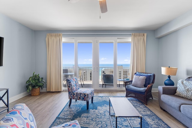 living area with wood finished floors, baseboards, and ceiling fan