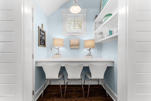 interior space featuring dark wood finished floors, vaulted ceiling, and baseboards