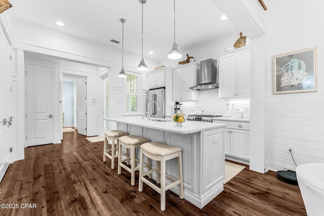 kitchen with light countertops, a kitchen bar, wall chimney exhaust hood, and white cabinetry