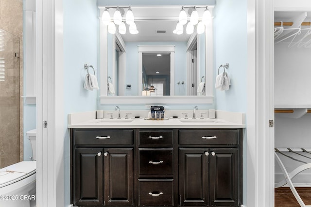 bathroom featuring a walk in closet, visible vents, a sink, and double vanity
