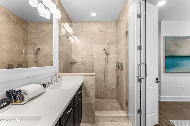 full bath with recessed lighting, a tile shower, double vanity, wood finished floors, and a sink