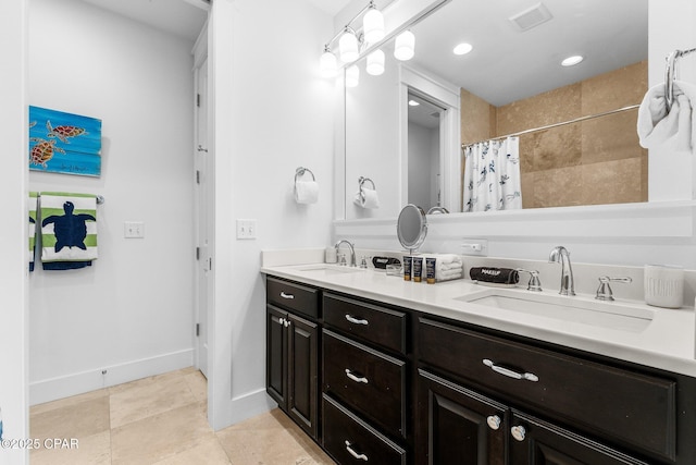 bathroom with curtained shower, double vanity, baseboards, and a sink